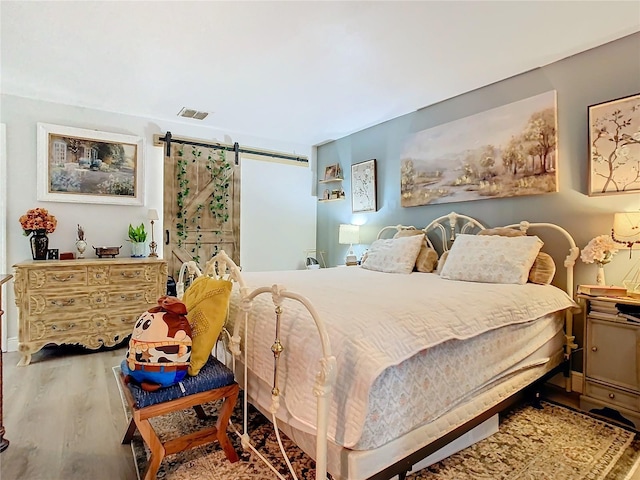 bedroom with a barn door and hardwood / wood-style floors