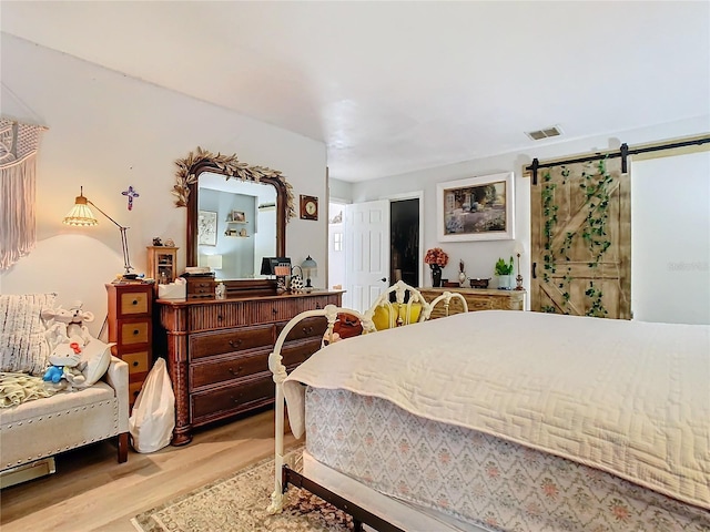 bedroom featuring a barn door and light hardwood / wood-style floors