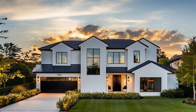 view of front of home featuring decorative driveway, a front yard, a standing seam roof, metal roof, and a garage