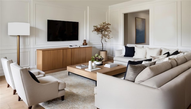 living room featuring light wood-style flooring and a decorative wall