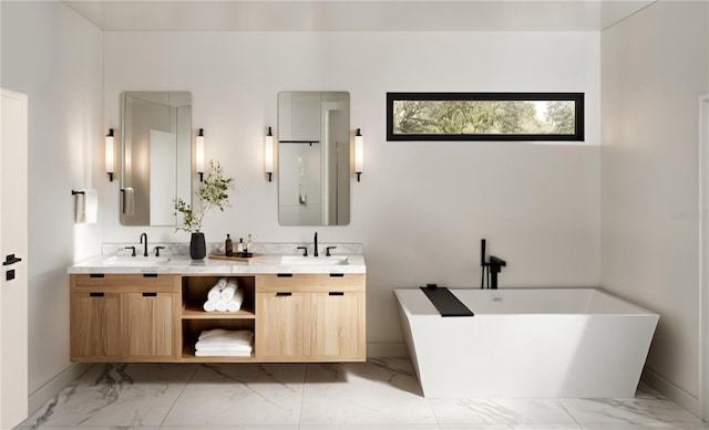 bathroom with double vanity, marble finish floor, a freestanding bath, and a sink