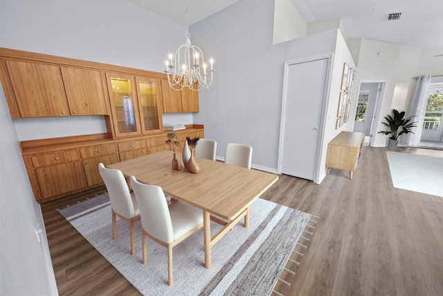 dining area with high vaulted ceiling, a notable chandelier, and light wood-type flooring