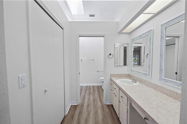 bathroom with wood-type flooring, toilet, and vanity