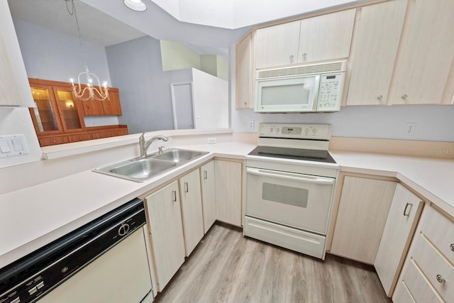 kitchen with sink, white appliances, a notable chandelier, kitchen peninsula, and light wood-type flooring