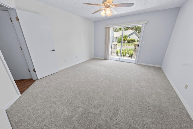 spare room featuring ceiling fan, light colored carpet, and a textured ceiling