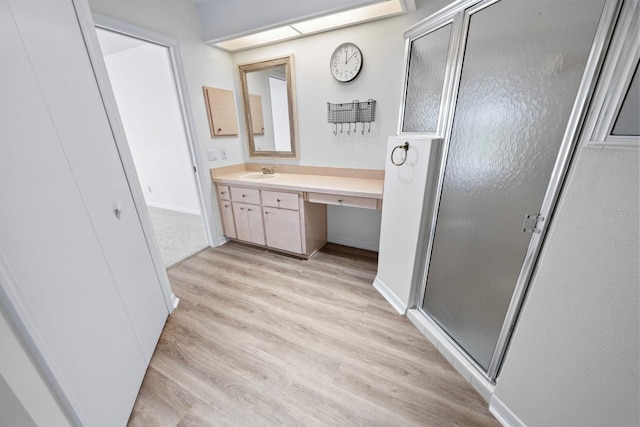 bathroom with hardwood / wood-style flooring, vanity, and a shower with door