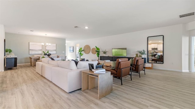 living room with light wood-type flooring and an inviting chandelier