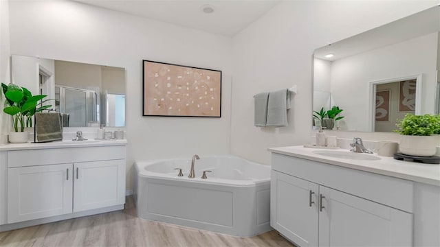 bathroom with hardwood / wood-style flooring, vanity, and plus walk in shower