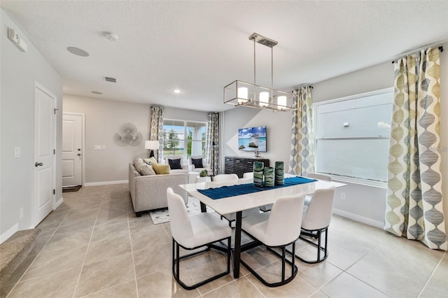 dining space featuring a textured ceiling, light tile patterned floors, and a notable chandelier