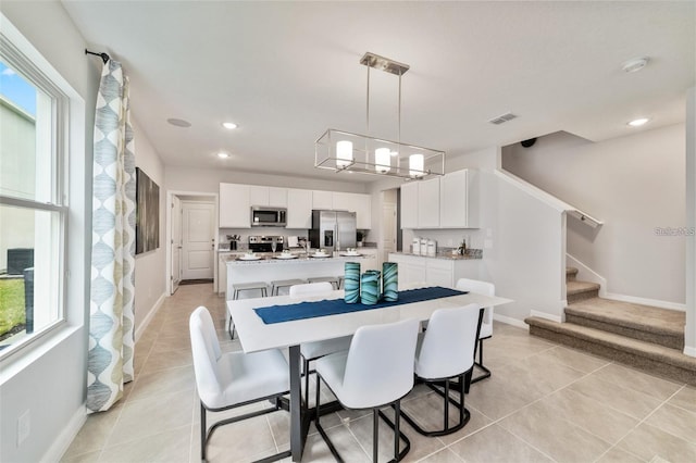 dining area with plenty of natural light, light tile patterned floors, and a chandelier