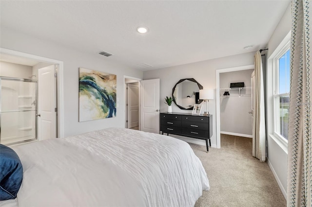 carpeted bedroom with a closet, ensuite bath, and multiple windows