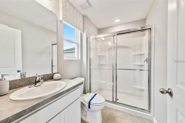 bathroom with an enclosed shower, vanity, toilet, and tile patterned flooring