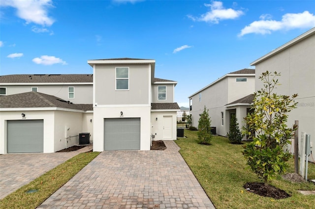 front of property with a garage, central AC, and a front lawn