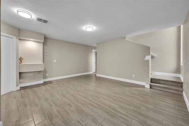 basement with light hardwood / wood-style floors and a textured ceiling