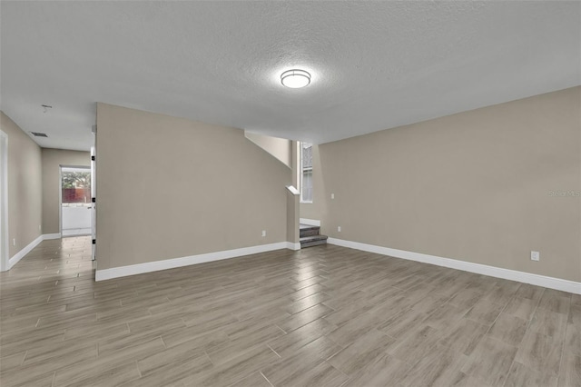 spare room featuring a textured ceiling and light wood-type flooring