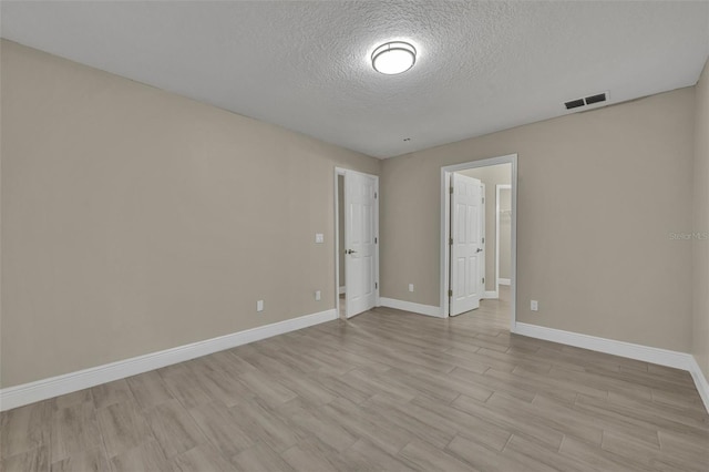 empty room featuring a textured ceiling and light hardwood / wood-style flooring