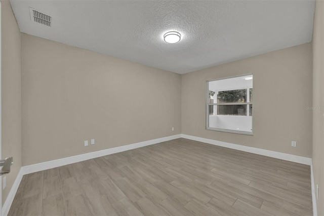 unfurnished room featuring a textured ceiling and light wood-type flooring