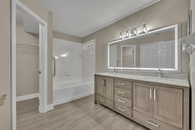 bathroom featuring vanity, a textured ceiling, and plus walk in shower