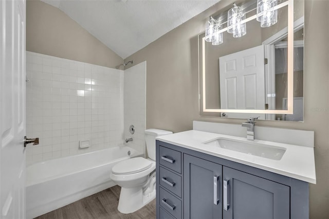 full bathroom featuring vaulted ceiling, tiled shower / bath, wood-type flooring, vanity, and toilet