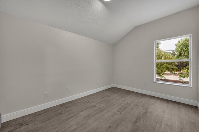 empty room featuring vaulted ceiling and light wood-type flooring