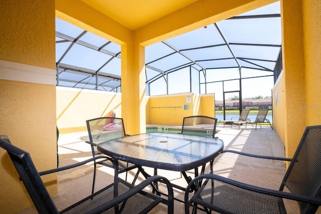 view of patio with a lanai and a water view