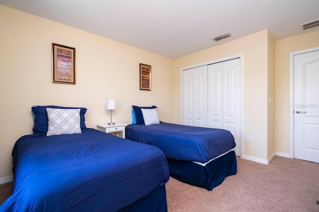 bedroom with light colored carpet, a textured ceiling, and a closet