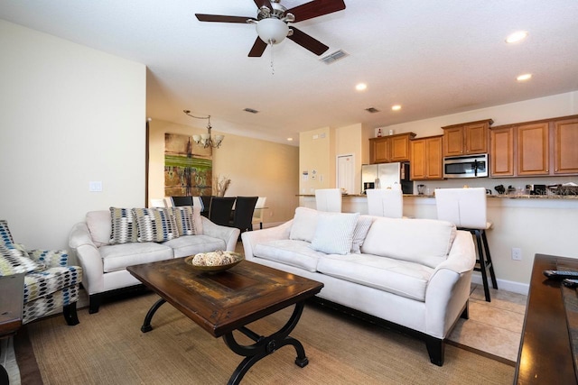 tiled living room with ceiling fan with notable chandelier