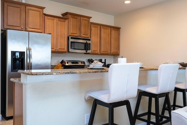 kitchen featuring appliances with stainless steel finishes, a kitchen bar, and light stone countertops