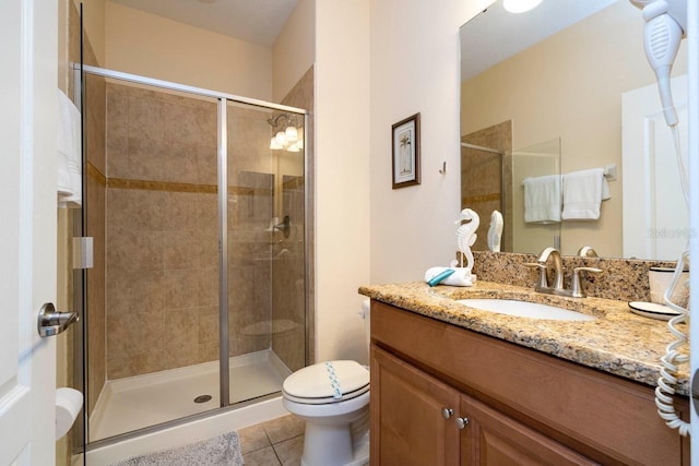 bathroom with an enclosed shower, vanity, toilet, and tile patterned flooring