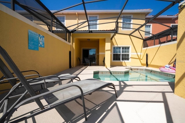 rear view of property featuring a patio area and glass enclosure