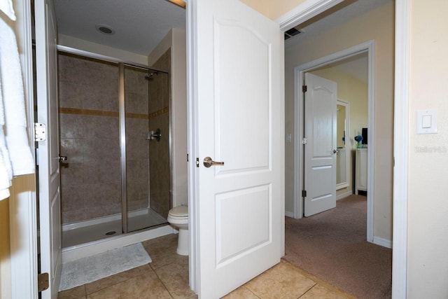 bathroom featuring toilet, an enclosed shower, and tile patterned flooring