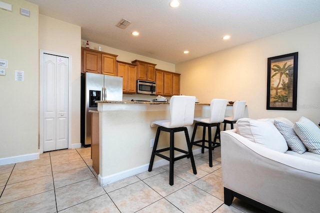 kitchen featuring light tile patterned flooring, a breakfast bar area, appliances with stainless steel finishes, and a kitchen island