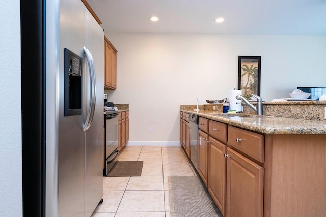 kitchen with light stone countertops, stainless steel appliances, sink, kitchen peninsula, and light tile patterned floors