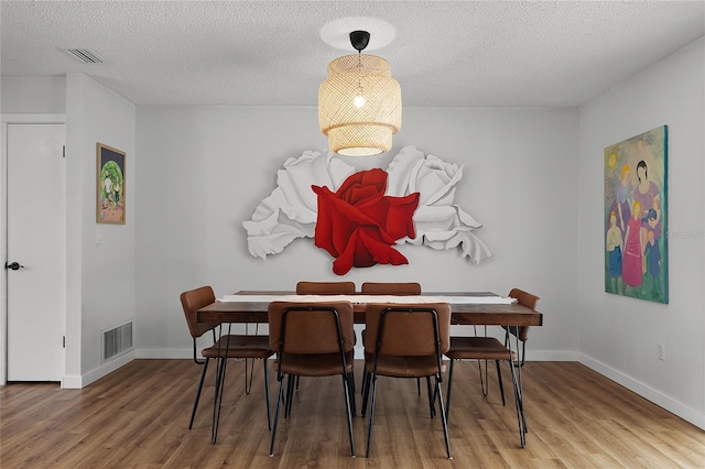 dining space featuring a textured ceiling and hardwood / wood-style flooring