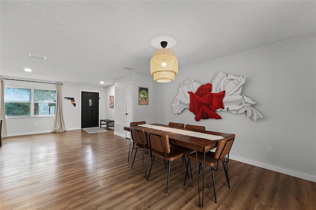 dining area with a textured ceiling and dark hardwood / wood-style floors