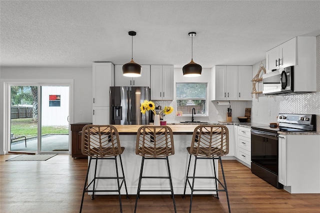 kitchen featuring a center island, a wealth of natural light, appliances with stainless steel finishes, a kitchen breakfast bar, and white cabinets