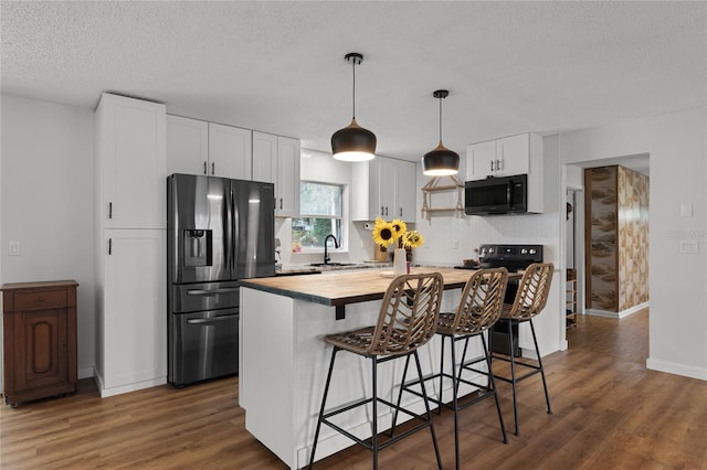 kitchen featuring white cabinets, a kitchen island, stainless steel refrigerator with ice dispenser, decorative light fixtures, and butcher block countertops