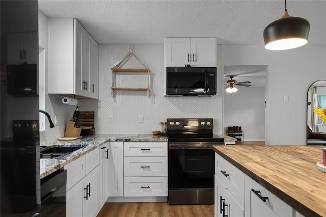 kitchen featuring wooden counters, white cabinetry, sink, ceiling fan, and electric range