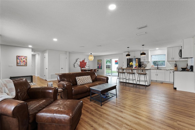 living room featuring a textured ceiling, light hardwood / wood-style floors, and sink