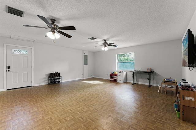 unfurnished living room with ceiling fan, a textured ceiling, and electric panel