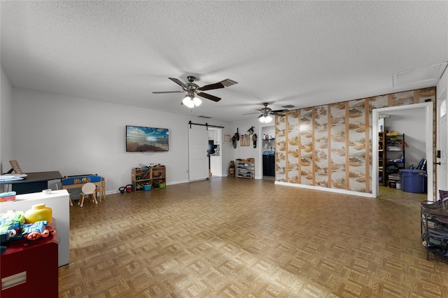 living room featuring a textured ceiling, ceiling fan, parquet floors, and a barn door