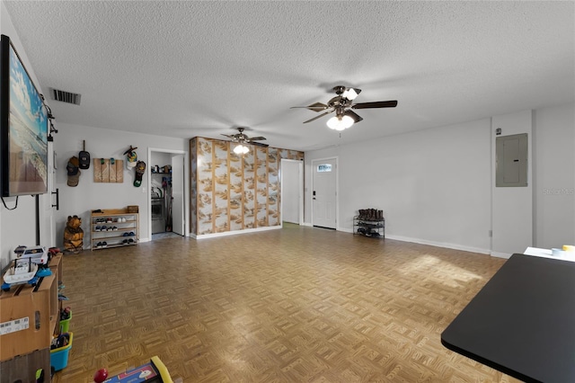 interior space featuring a textured ceiling, ceiling fan, electric panel, and parquet floors