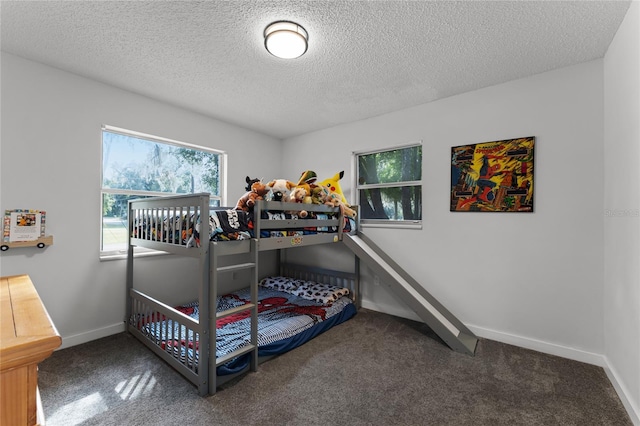 bedroom with a textured ceiling and dark colored carpet