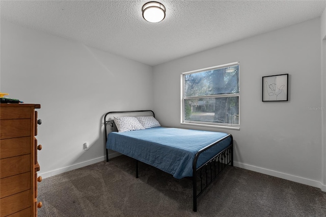 bedroom with a textured ceiling and dark carpet