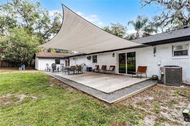 back of property with central AC unit, a patio area, and a lawn