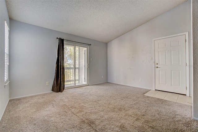 spare room with light colored carpet, a textured ceiling, and lofted ceiling