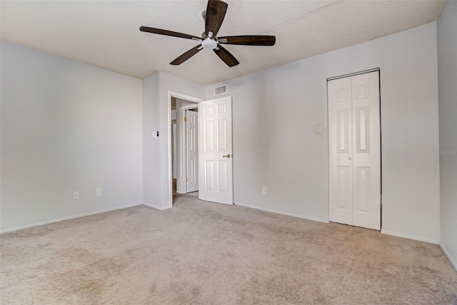 unfurnished bedroom with a textured ceiling, light colored carpet, and ceiling fan