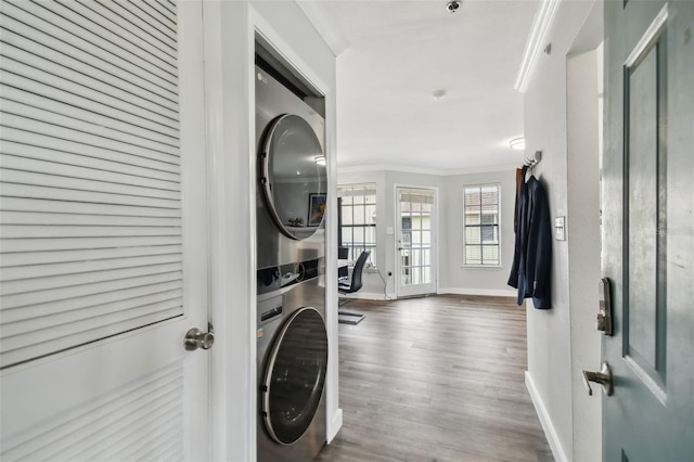 clothes washing area with ornamental molding, stacked washer / drying machine, and dark hardwood / wood-style floors