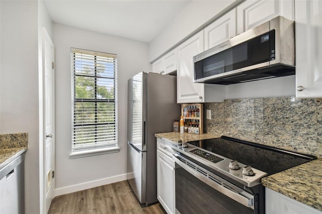 kitchen with light stone counters, white cabinets, light hardwood / wood-style flooring, and stainless steel appliances