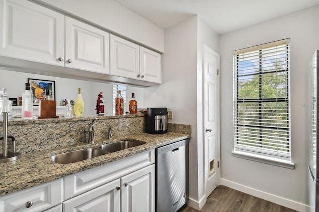 kitchen with light stone countertops, white cabinetry, sink, dark hardwood / wood-style floors, and stainless steel dishwasher